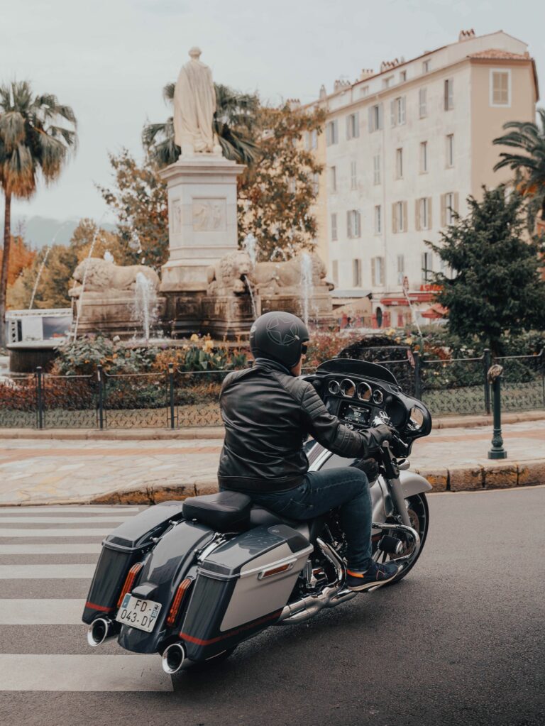 Moto traversant une place du centre-ville d'Ajaccio, près de la statue et de la fontaine
